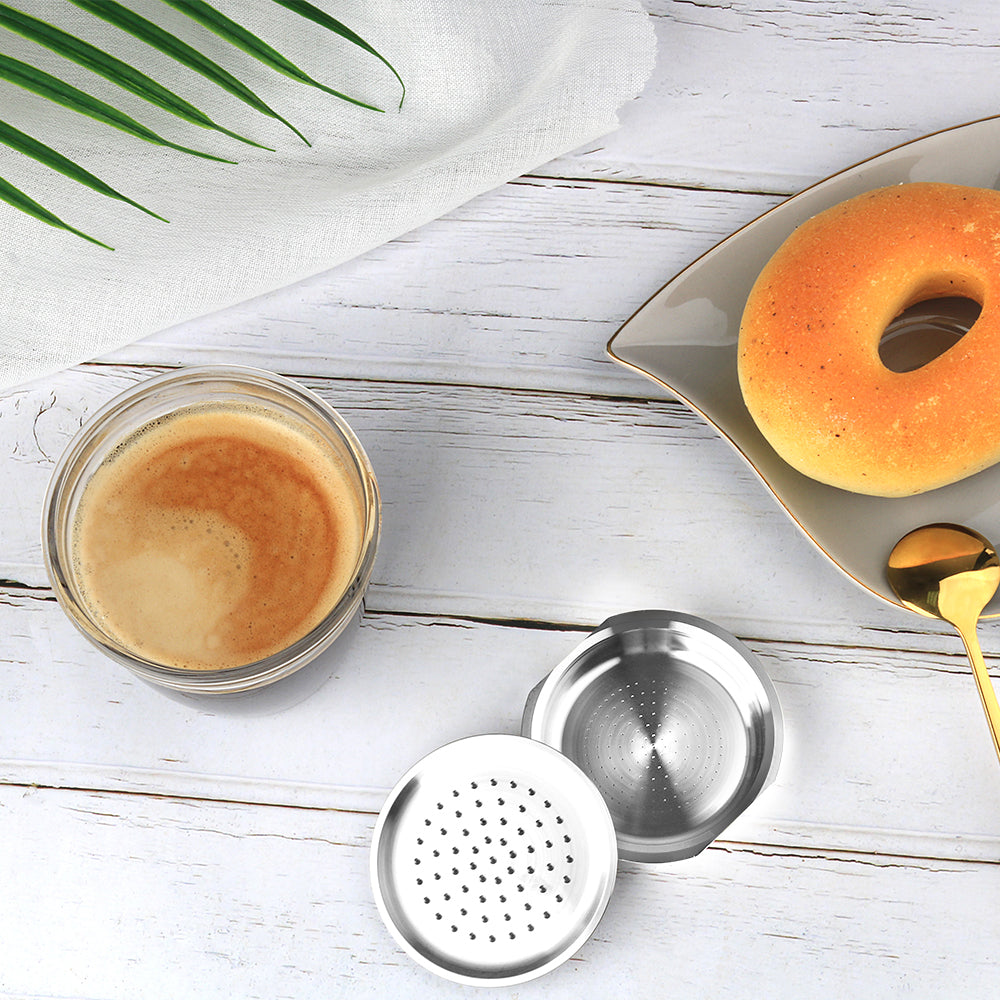 A coffee machine brewing espresso with a ceramic mark cup, accompanied by a donut on a plate.